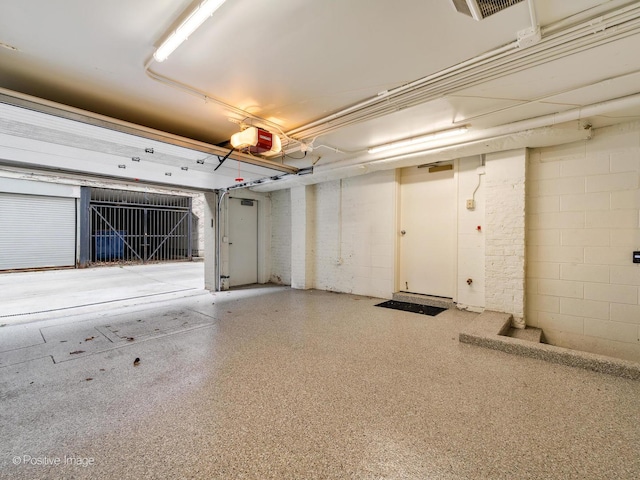 garage featuring concrete block wall and a garage door opener