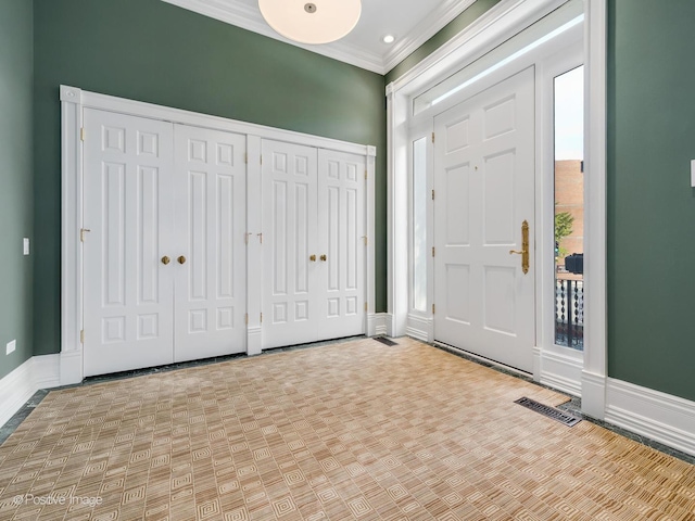 foyer featuring baseboards, visible vents, and crown molding
