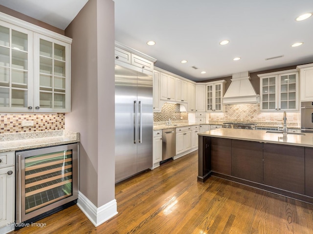 kitchen featuring custom range hood, appliances with stainless steel finishes, wine cooler, and dark wood finished floors