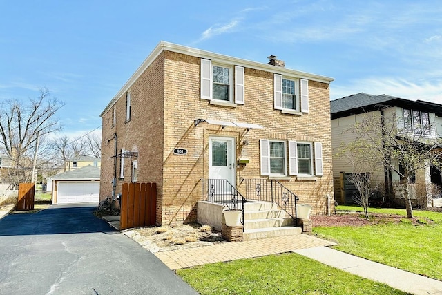 view of front of home featuring a chimney, brick siding, an outbuilding, a garage, and a front yard