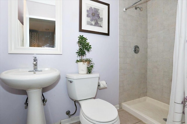 bathroom with toilet, a stall shower, and a sink