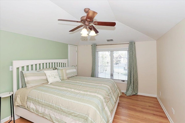 bedroom with lofted ceiling, visible vents, ceiling fan, baseboards, and light wood finished floors