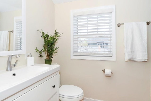 bathroom featuring baseboards, toilet, vanity, and plenty of natural light