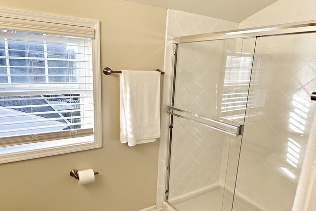 bathroom featuring a wealth of natural light, a shower stall, and baseboards