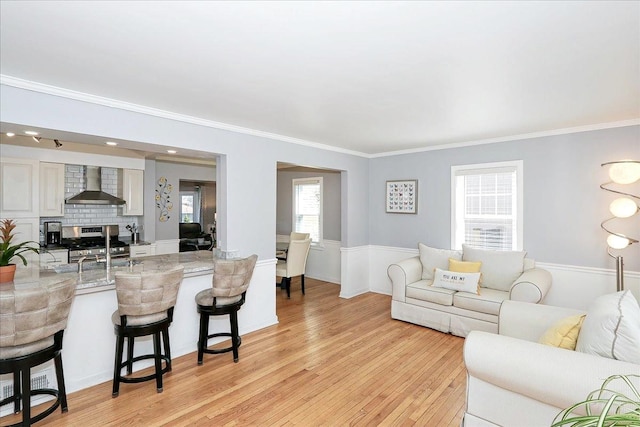 living area with light wood-type flooring and crown molding