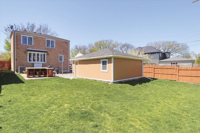 rear view of property with a yard, an outbuilding, brick siding, and a fenced backyard