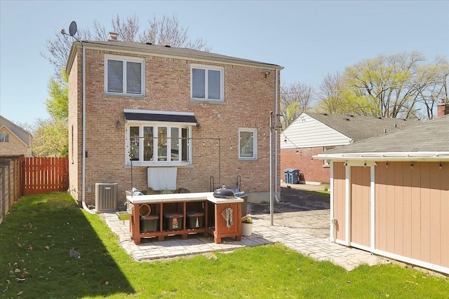back of house featuring a yard, brick siding, fence private yard, central air condition unit, and a patio
