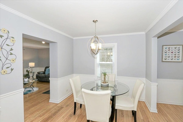 dining area featuring ornamental molding, light wood-type flooring, and a notable chandelier