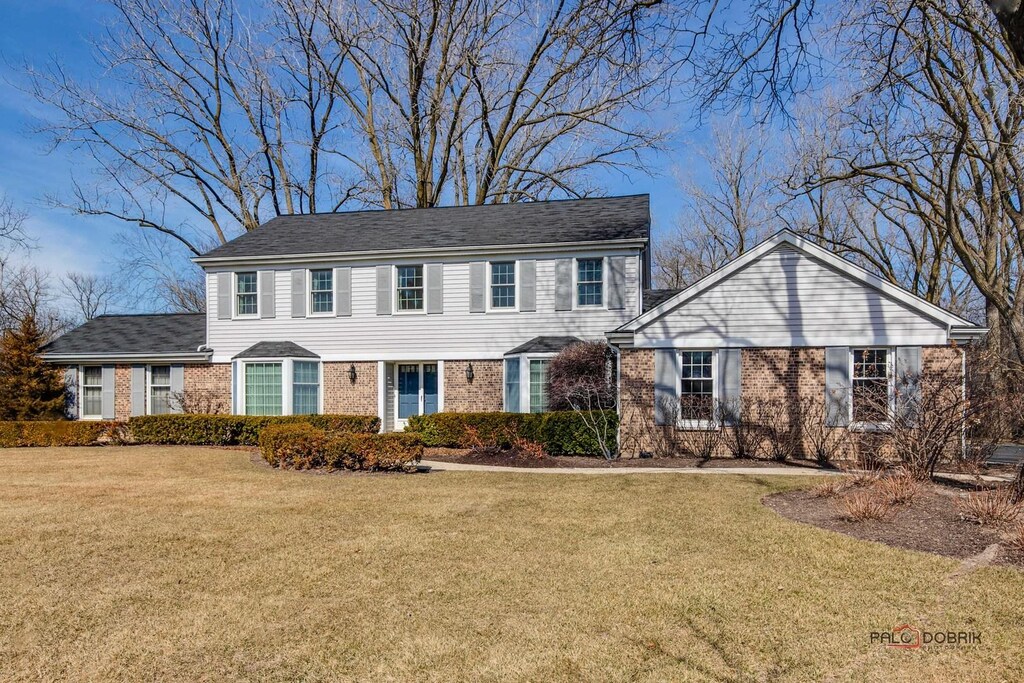 colonial inspired home with brick siding and a front yard