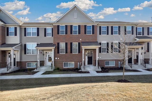 multi unit property featuring brick siding and a front lawn