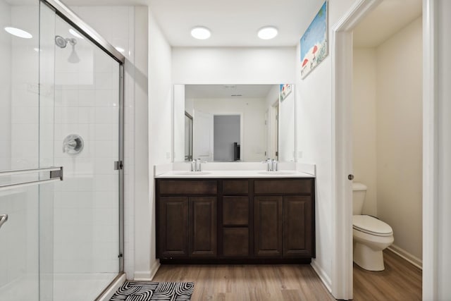 bathroom with toilet, a stall shower, and wood finished floors