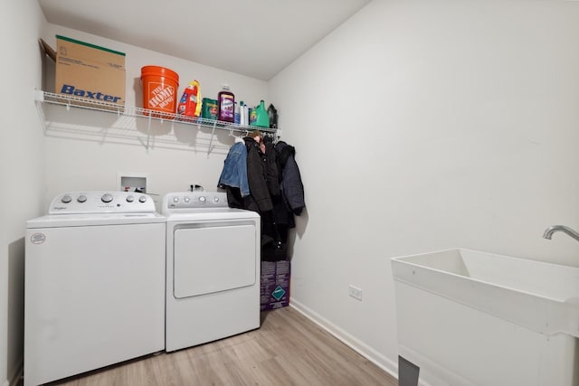 laundry room featuring a sink, separate washer and dryer, light wood-style flooring, laundry area, and baseboards