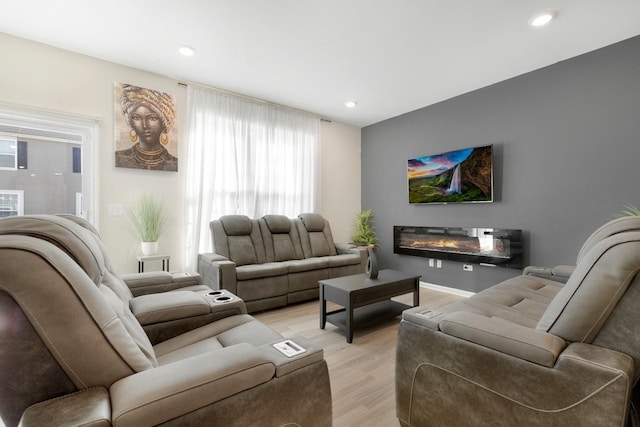 living area with a glass covered fireplace, light wood-style floors, and recessed lighting
