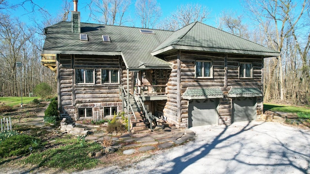 2655 County Road 550 E, Mahomet, IL 61853 - log-style house with stairs, a garage, a chimney, log siding, and driveway