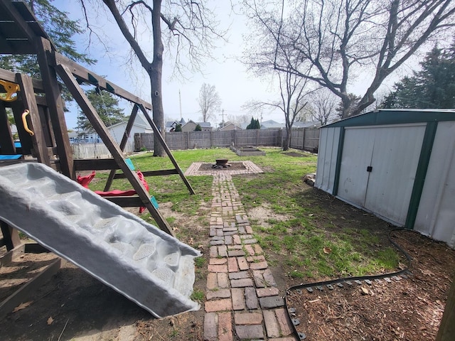 view of yard with a shed, a fenced backyard, an outdoor structure, and a playground