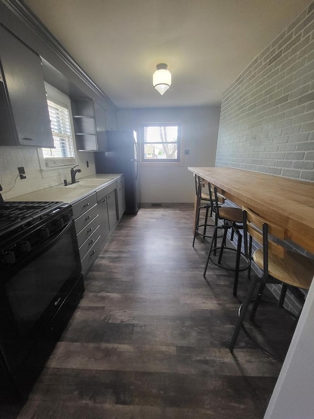 dining area featuring a healthy amount of sunlight, brick wall, dark wood finished floors, and baseboards