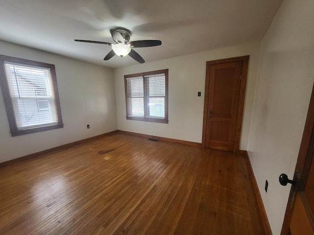 empty room featuring visible vents, baseboards, a ceiling fan, and wood finished floors