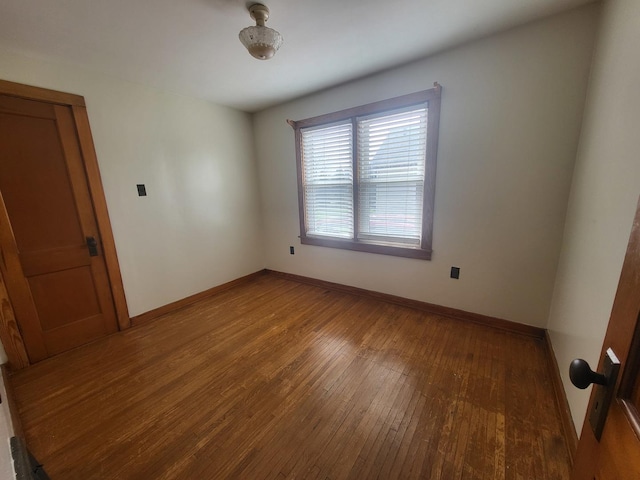 spare room with baseboards and hardwood / wood-style flooring