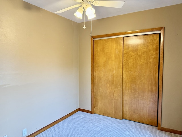 unfurnished bedroom with baseboards, carpet flooring, ceiling fan, and a closet