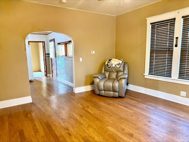 unfurnished room featuring baseboards, wood finished floors, and arched walkways