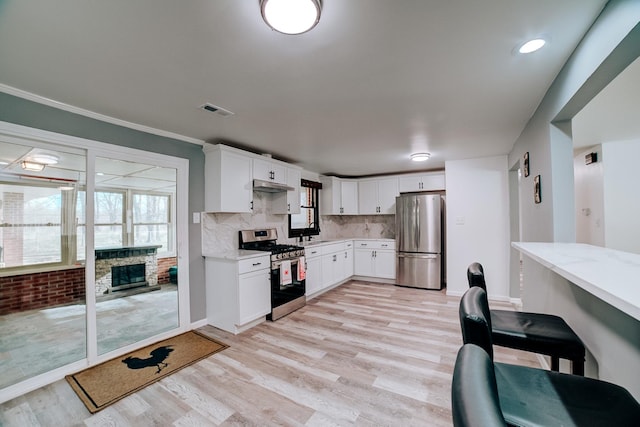 2775 E Riverview Dr, Kankakee, IL 60901 - kitchen featuring stainless steel appliances, decorative backsplash, visible vents, light wood-style flooring, and light stone countertops