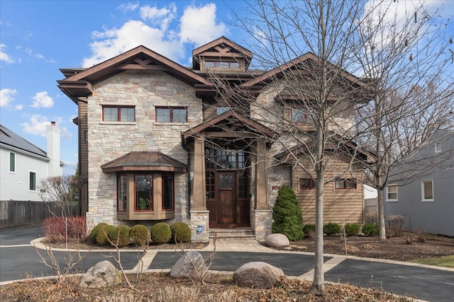 view of front facade with fence and stone siding