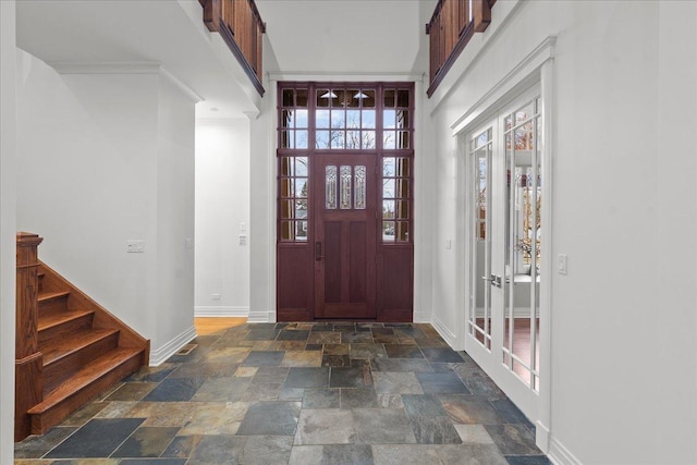 entryway featuring french doors, stone finish flooring, baseboards, and stairway