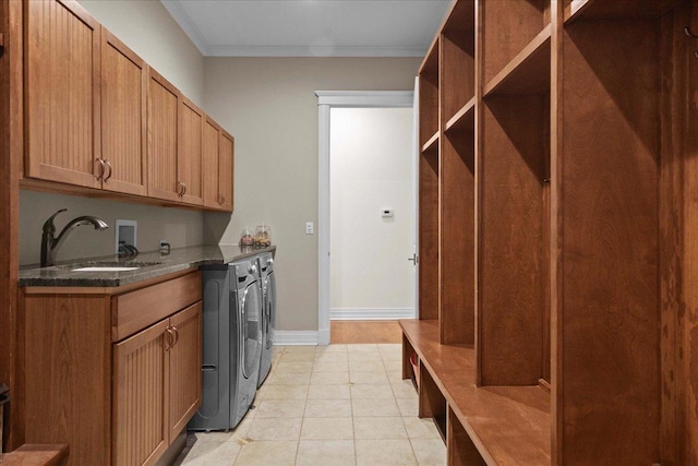 laundry room featuring ornamental molding, a sink, washer and clothes dryer, cabinet space, and light tile patterned floors