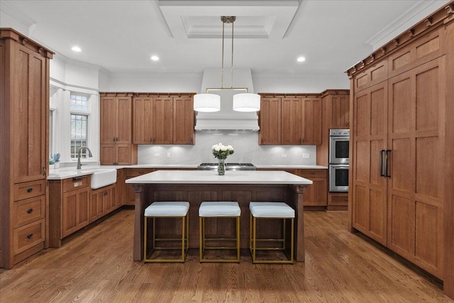 kitchen featuring a kitchen breakfast bar, light countertops, a kitchen island, a sink, and brown cabinets