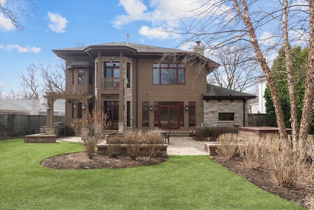 back of house featuring a chimney, a hot tub, a pergola, a patio, and a lawn