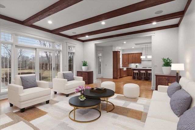 living room featuring baseboards, light wood-style flooring, beam ceiling, and recessed lighting