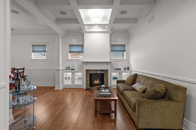 living area featuring a tiled fireplace, wood finished floors, crown molding, and visible vents