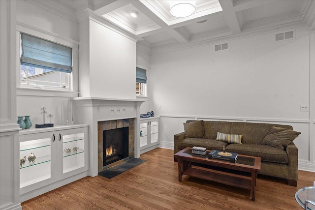 living room with a tile fireplace, visible vents, coffered ceiling, and wood finished floors