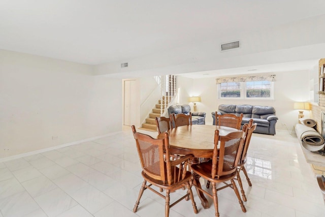 dining space featuring light tile patterned floors, baseboards, visible vents, and stairs