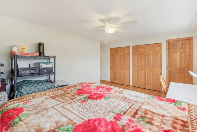 bedroom with two closets, light wood finished floors, and a ceiling fan