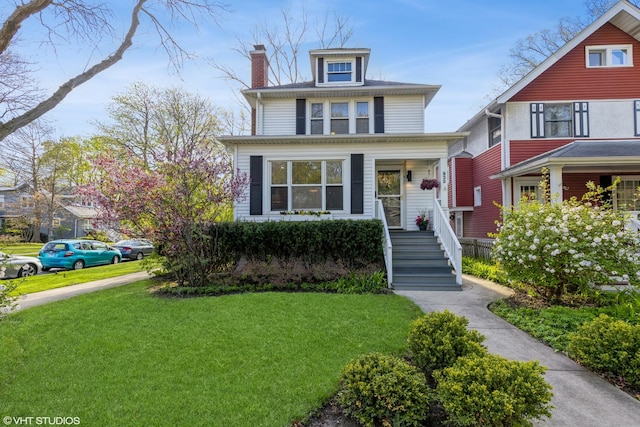 american foursquare style home with a chimney and a front yard