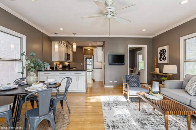 living area with light wood finished floors, a ceiling fan, baseboards, crown molding, and recessed lighting