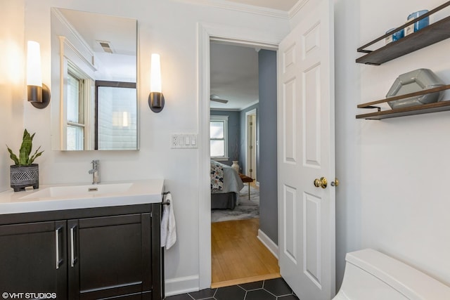 bathroom with vanity, toilet, ornamental molding, ensuite bathroom, and baseboards
