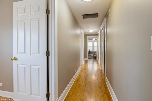 corridor with light wood-style flooring and baseboards