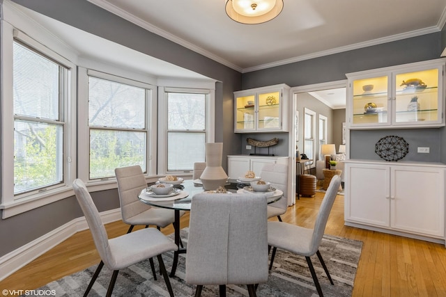 dining area with plenty of natural light, crown molding, light wood-type flooring, and baseboards