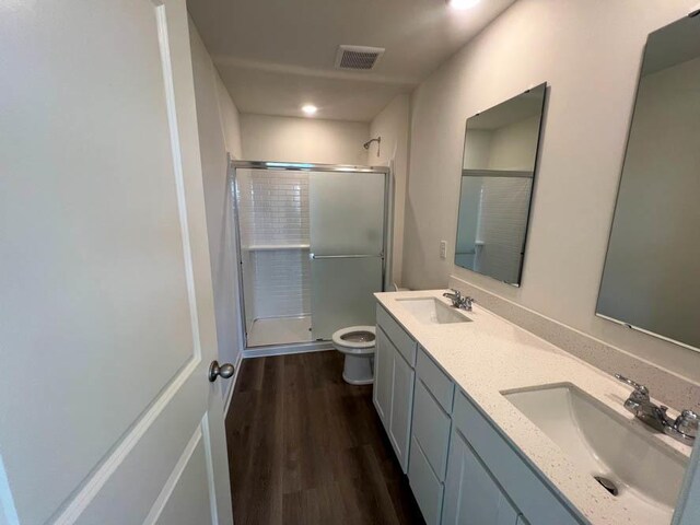 full bath featuring visible vents, a sink, a shower stall, and wood finished floors