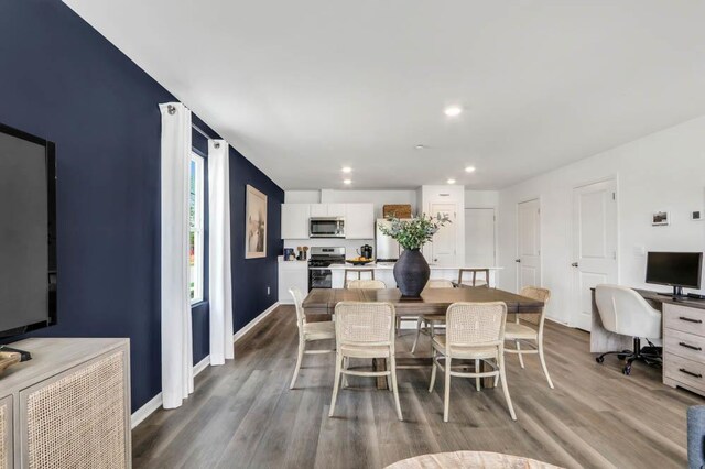 dining space featuring baseboards, wood finished floors, and recessed lighting