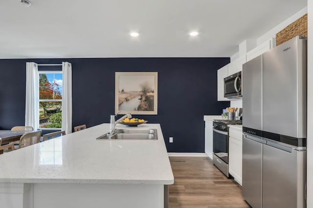 kitchen featuring light wood-style flooring, white cabinetry, a sink, and stainless steel appliances