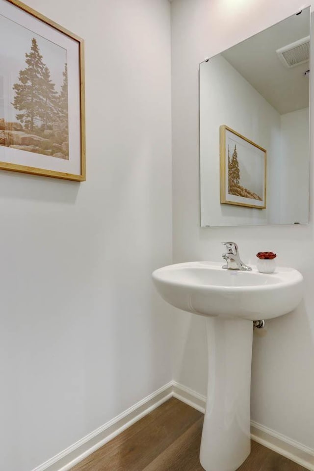 bathroom with baseboards, visible vents, wood finished floors, and a sink