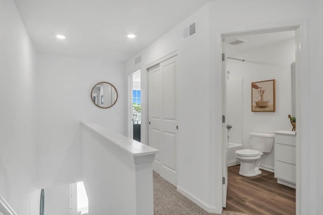 hall with baseboards, visible vents, and recessed lighting