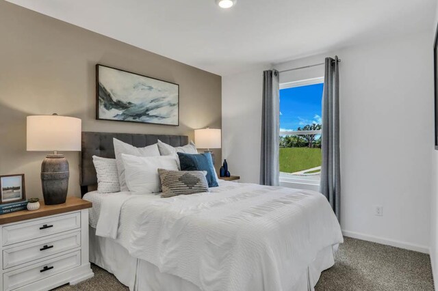 bedroom featuring baseboards and dark carpet