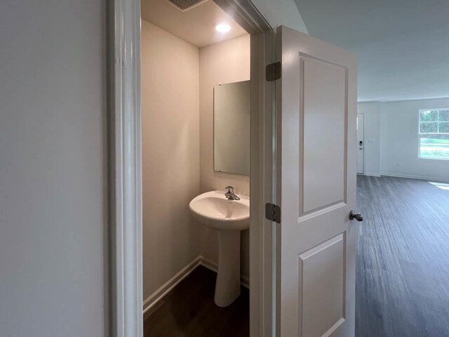 bathroom featuring visible vents, a sink, baseboards, and wood finished floors