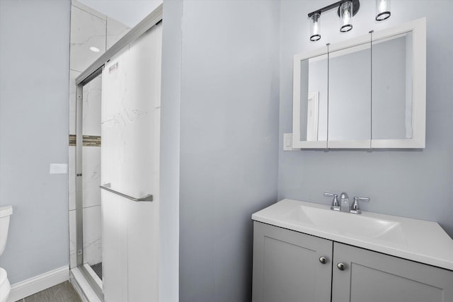 full bath with a stall shower, baseboards, toilet, and vanity