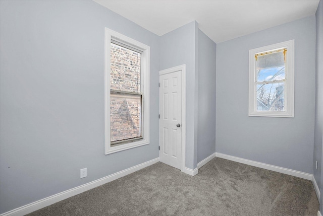 carpeted empty room featuring baseboards
