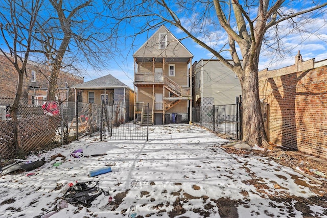 snow covered house featuring a gate and a fenced front yard